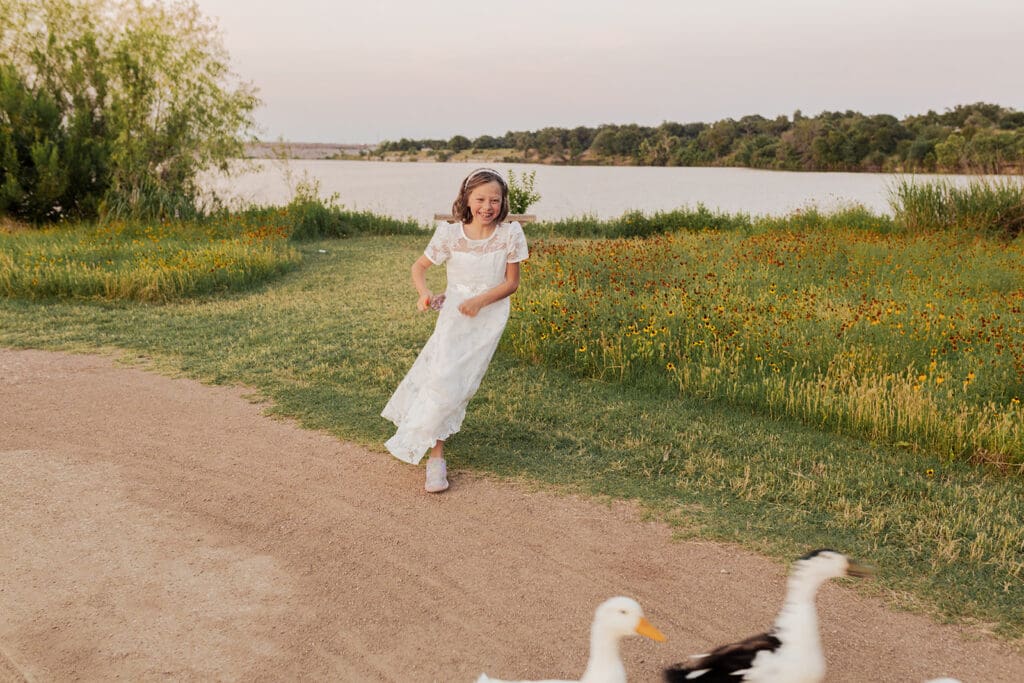 Smiling child in white outfit during LDS baptism photos in nature