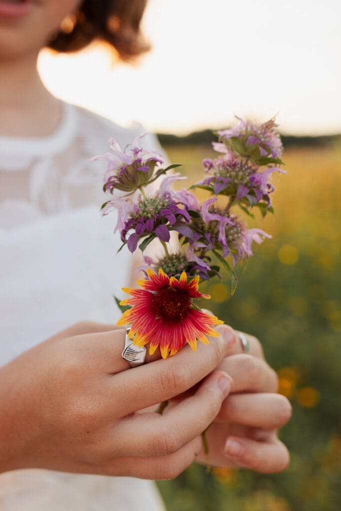 Cami holding a flower amoung a field of flowers. 