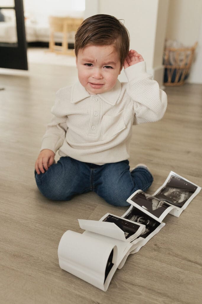 Big sibling pouting at ultrasound photo during cozy maternity shoot in Bulverde