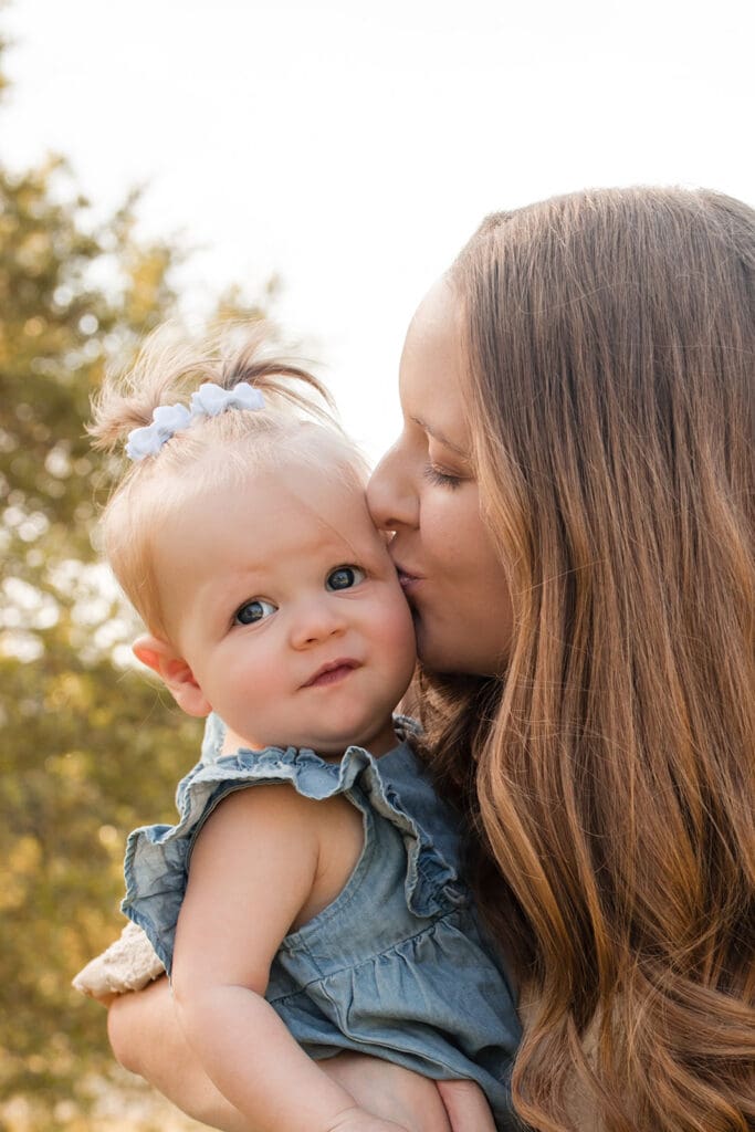 Mother kissing baby in a field of wildflowers near Bulverde


