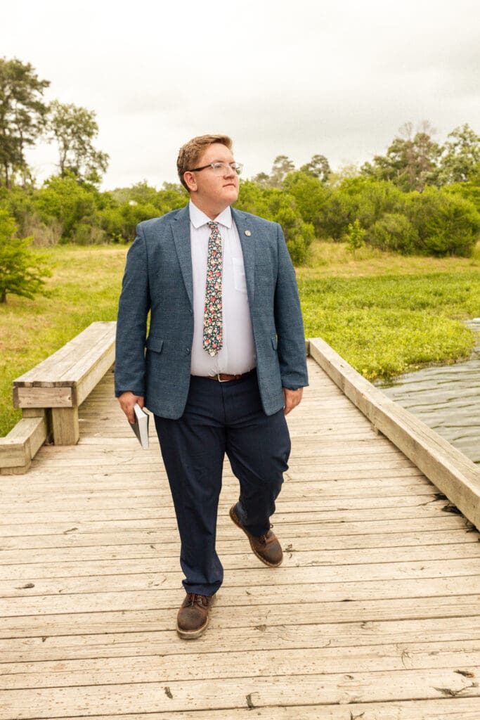 Young LDS missionary in suit and tie holding flag of mission location in Spring, Texas

