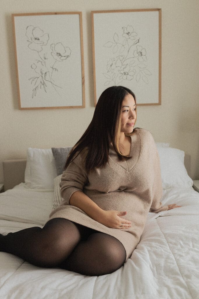 Mother-to-be sitting comfy bed during lifestyle maternity shoot