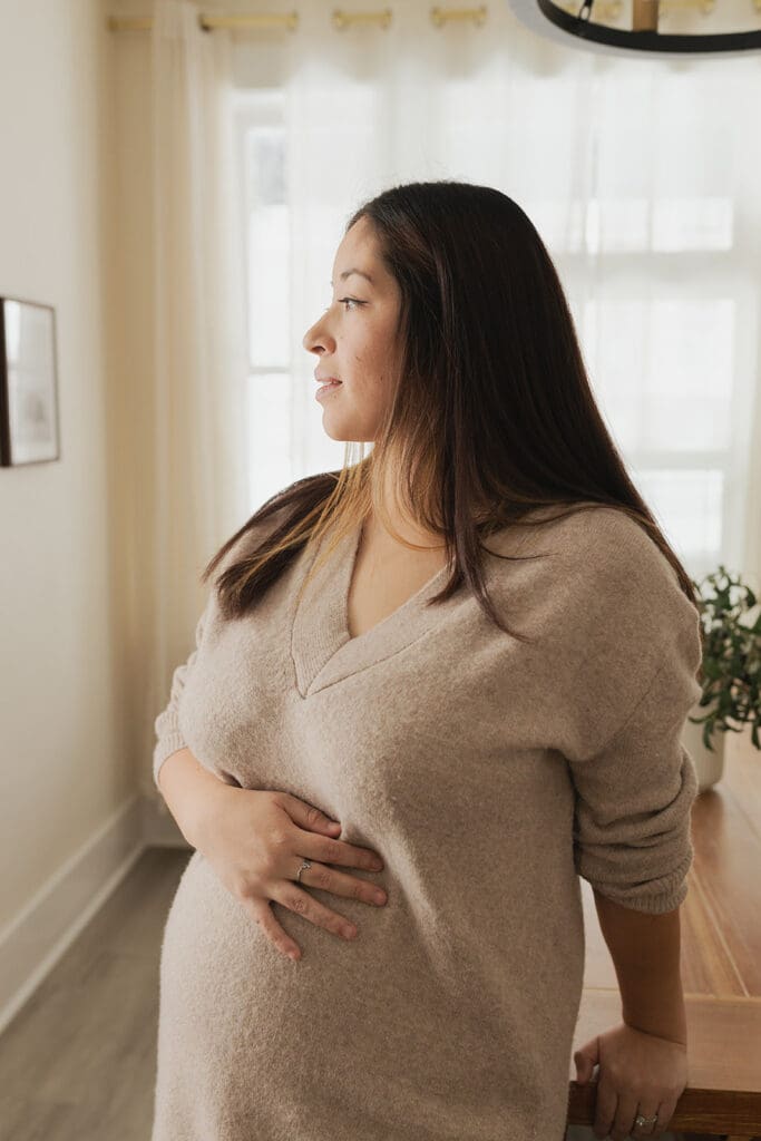 Expecting mother holding belly in calm indoor space in Bulverde